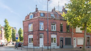 Ein rot backsteiner Gebäude mit weißer Tür und Fenstern, an einer Straßenecke gelegen.