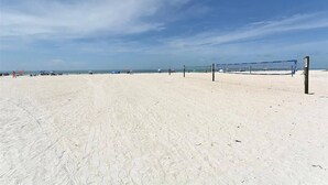 Ein Beachvolleyballfeld mit Netz, Sand und blauem Himmel.