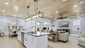 A modern kitchen with a large island, white cabinetry, and pendant lighting. - Lucky Catch: Free golf cart, Walk to beach, Heated pool behind house, Game room (Miramar Beach)