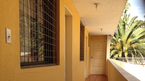 A corridor with yellow walls, a tiled floor, barred windows, and a door. - ALSTON INN HOTEL (Quito)
