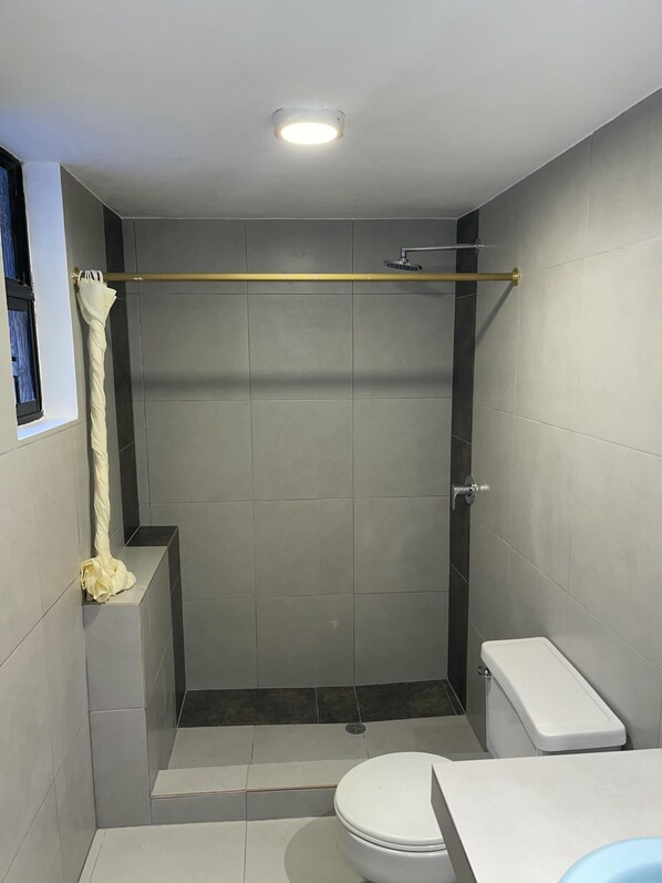A small, modern bathroom with a shower, toilet, and sink.