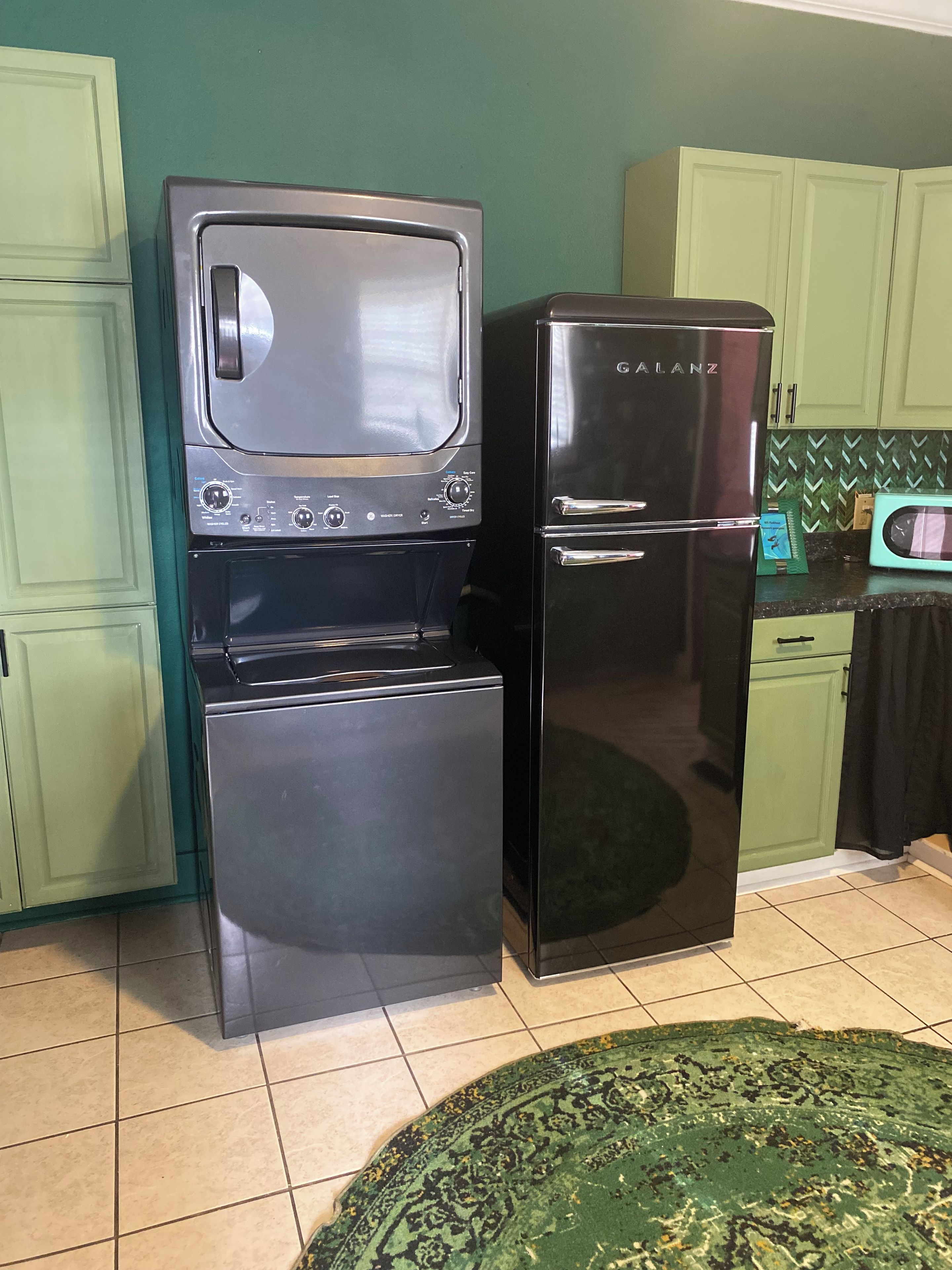 Una cucina con un frigorifero nero, un forno a microonde e un piano cottura.