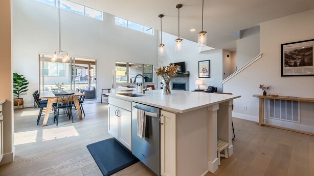 A spacious kitchen with a large island, pendant lights, and a view to the backyard.