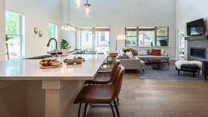A spacious kitchen with a large island, a dining area with chairs, a sofa, and a fireplace.