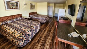 Een hotelkamer met twee bedden, een bureau, een telefoon, een televisie en een spiegel.