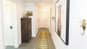 A hallway with a patterned rug, a wooden cabinet, and framed artwork on the walls. - Luxurious Crested Butte Home | 4 Bedroom | Walk to Elk | Gas Grill | Mtn Views (Crested Butte)