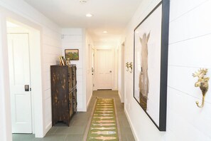 A hallway with a patterned rug, a wooden cabinet, and framed artwork on the walls. - Luxurious Crested Butte Home | 4 Bedroom | Walk to Elk | Gas Grill | Mtn Views (Crested Butte)