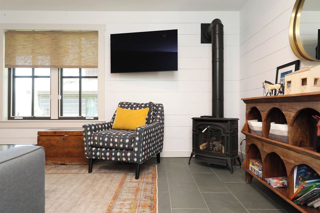 A living room with a patterned armchair, a television, a fireplace, and a bookshelf.