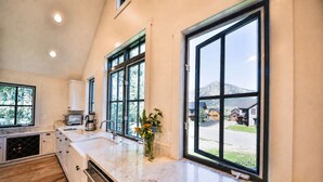A modern kitchen with a large window, a built-in oven, and a countertop with a vase of flowers. - Luxurious Crested Butte Home | 4 Bedroom | Walk to Elk | Gas Grill | Mtn Views (Crested Butte)
