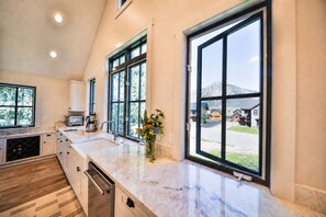 A modern kitchen with a large window, a built-in oven, and a countertop with a vase of flowers. - Luxurious Crested Butte Home | 4 Bedroom | Walk to Elk | Gas Grill | Mtn Views (Crested Butte)