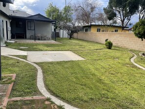 Enjoy a serene outdoor space with a patio, lawn, and seating area surrounded by trees and a brick wall.