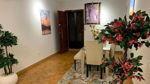 Zona de dinar amb un sòl de fusta en relleu, taula de dinar amb cadires, un estotge decoratiu i plantes en testos.