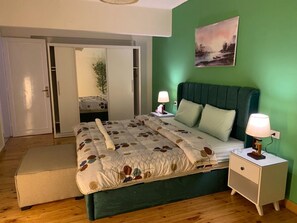 Une chambre à coucher avec un lit, des tables de chevet, une commode, un miroir et un mur vert.