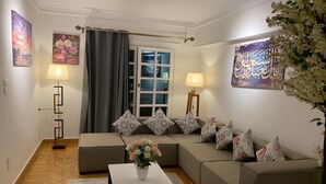Un saló amb un sofà, dues làmpades de peu, una taula de centre i una finestra amb cortines.