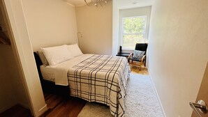 Une chambre à coucher avec un lit, une chaise, une fenêtre et un lustre.