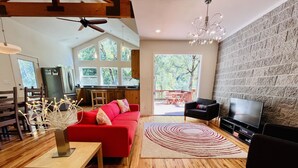 Un salon moderne avec un canapé rouge, un plancher en bois, un téléviseur et un mur en pierre.