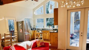 Un salon spacieux avec un canapé rouge, un parquet en bois et une grande fenêtre.