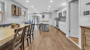 Una cocina moderna con armarios blancos, una mesa de comedor de madera y un horno empotrado.