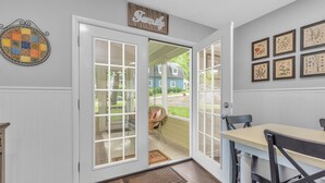 Una cocina con una puerta blanca que da a un patio, un letrero de madera sobre la puerta e impresiones botánicas enmarcadas en la pared.