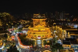 A traditional multi-tiered building with illuminated windows and a surrounding street at night. - Mengfei Hotel (Liuzhou Yaobu Old Town) (Liuzhou)