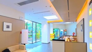 A hotel lobby with a reception desk, a sofa, and a large window. - Mengfei Hotel (Liuzhou Yaobu Old Town) (Liuzhou)