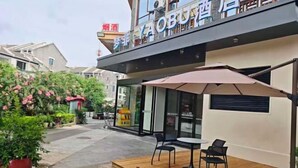 An outdoor seating area with a table and chairs, a fire hydrant, and a building with a sign. - Mengfei Hotel (Liuzhou Yaobu Old Town) (Liuzhou)