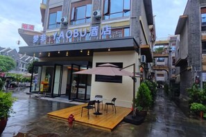 A hotel with a covered outdoor seating area, a fire hydrant, and a narrow street. - Mengfei Hotel (Liuzhou Yaobu Old Town) (Liuzhou)