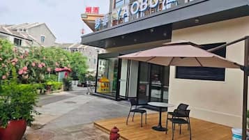Un espacio al aire libre con una mesa, sillas, un hidrante y un edificio con un letrero.