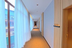 A hotel corridor with a carpeted floor, a wooden door with a number, and a window with curtains. - Mengfei Hotel (Liuzhou Yaobu Old Town) (Liuzhou)