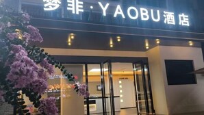 A hotel entrance with a glass door, illuminated signage, and a purple flowering plant in the foreground. - Mengfei Hotel (Liuzhou Yaobu Old Town) (Liuzhou)