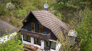 Una casa a due piani con un balcone, un'antenna parabolica e un piccolo deposito.