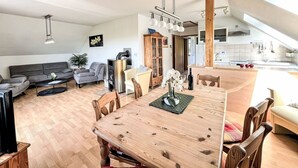 Un'ampia zona giorno con tavolo da pranzo, divani e una cucina sullo sfondo.