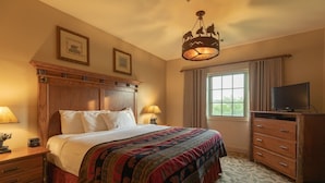 A hotel room with a large bed, wooden headboard, a television on a wooden cabinet, and a window with curtains. - Feb 10th-17th - Beautiful Lodge, Scenic Views, Family Friendly (Ridgedale)