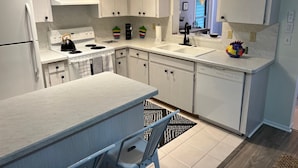 Una cocina moderna con armarios blancos, un lavamanos doble y una estufa.