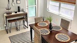 Un comedor con una mesa de madera, sillas tejidas y un ventilador de techo.