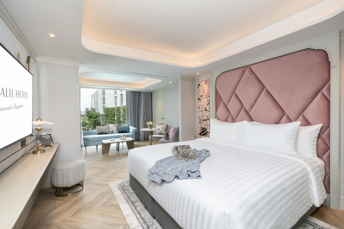 Una habitación de hotel moderna con una cama grande, un escritorio y vistas al exterior.