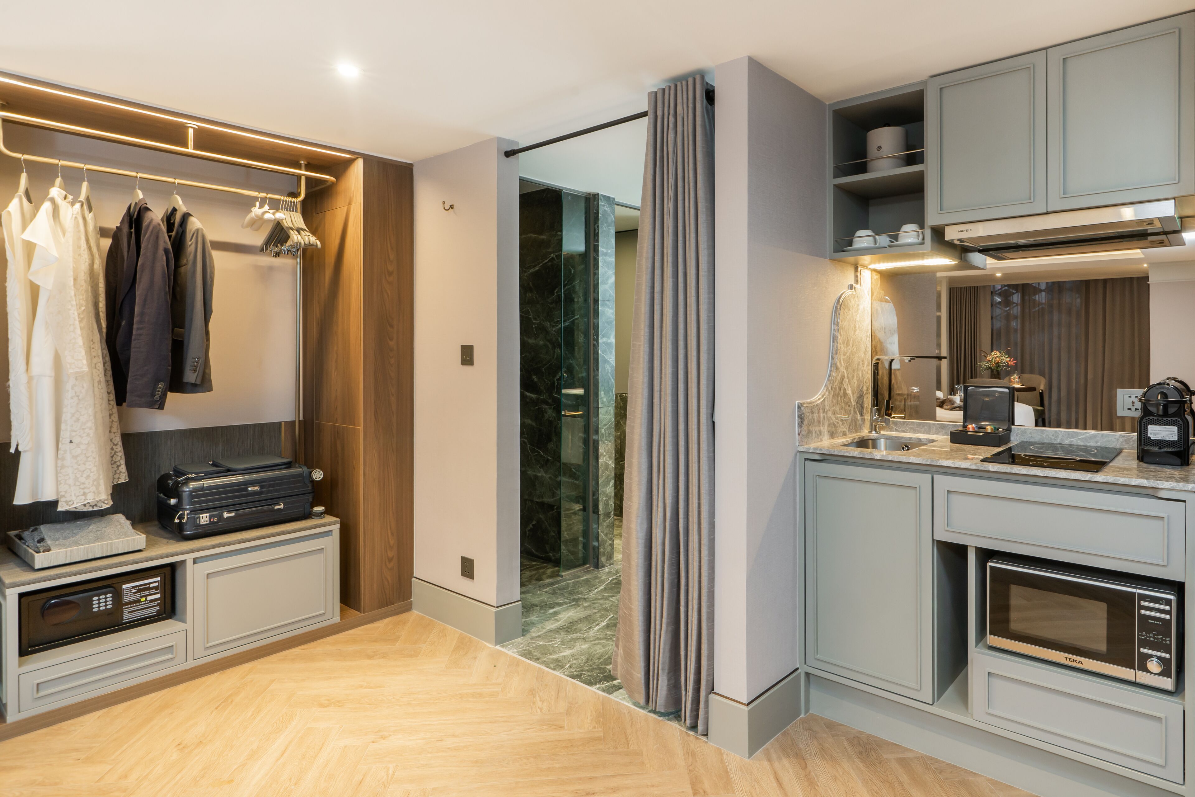A modern kitchen with built-in appliances, a dining area, and a walk-in closet with hanging clothes.