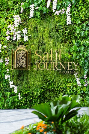 Un muro de jardín exuberante con el texto "Sall Journey Riverside" y un emblema decorativo.