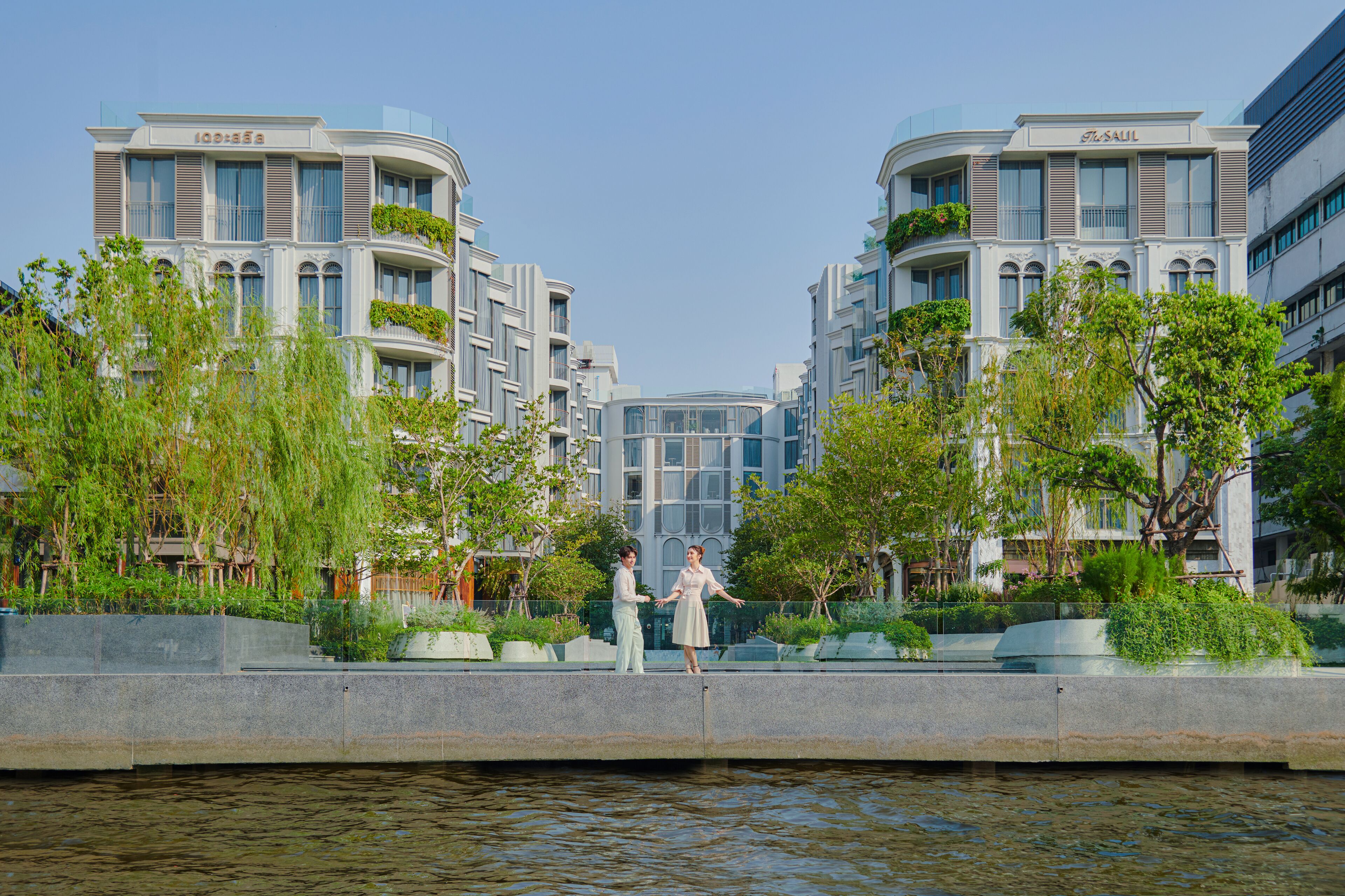 A modern building with balconies and a water body in front.