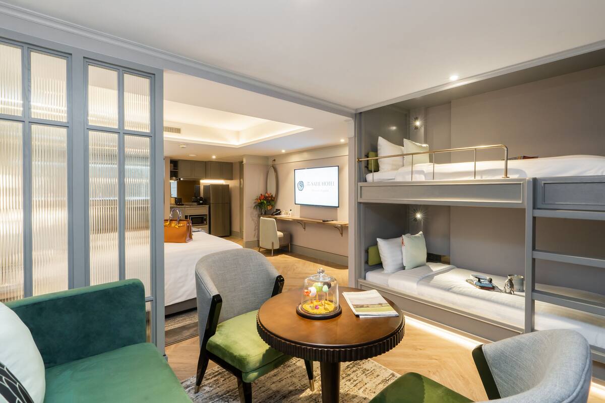 Hotelkamer met een stapelbed, een bureau, een stoel, een kleintje tafeltje met een decoratief object en een televisie.