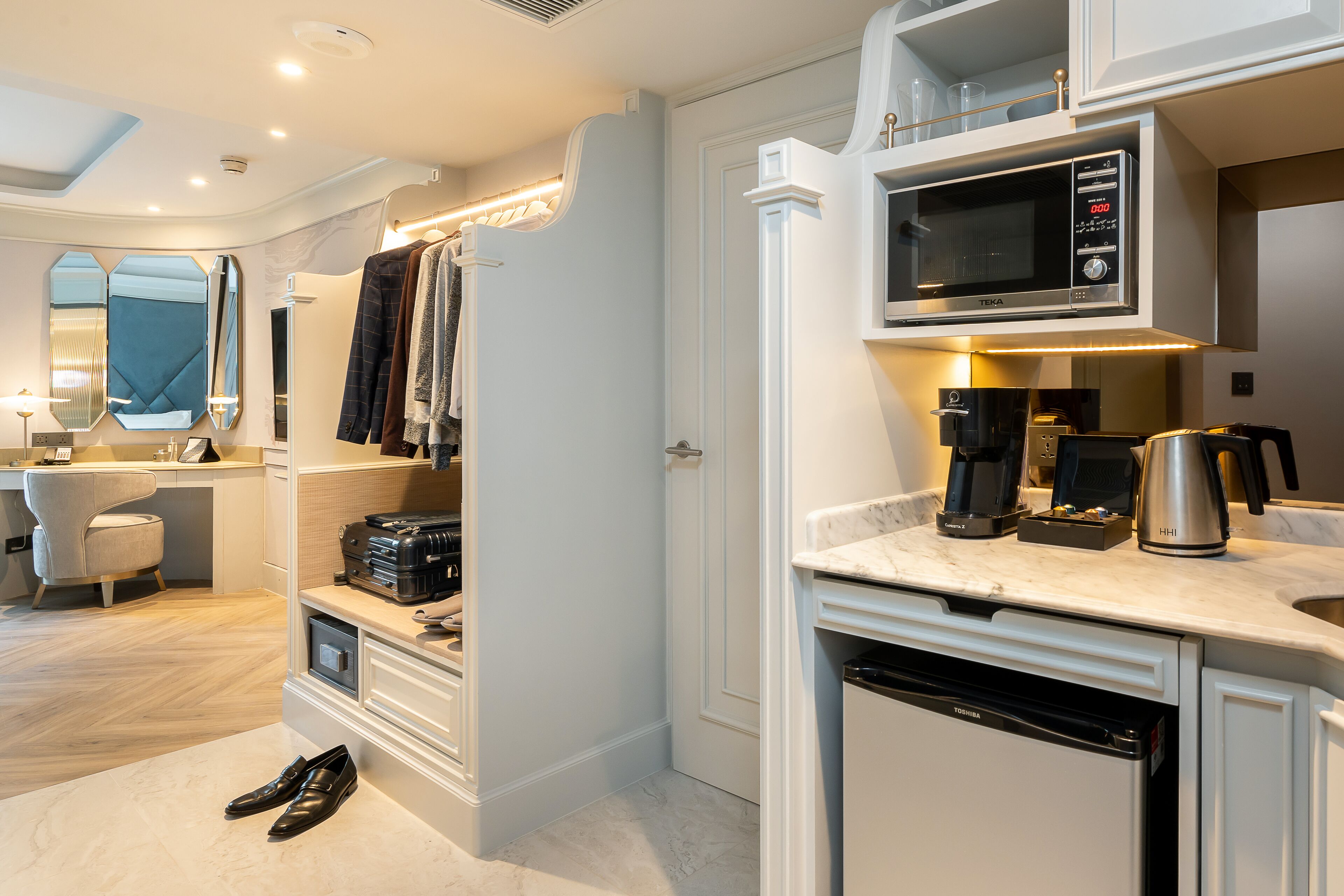 A modern kitchen with a built-in microwave, coffee maker, and toaster. There is a white dishwasher and a countertop with a marble-like surface.