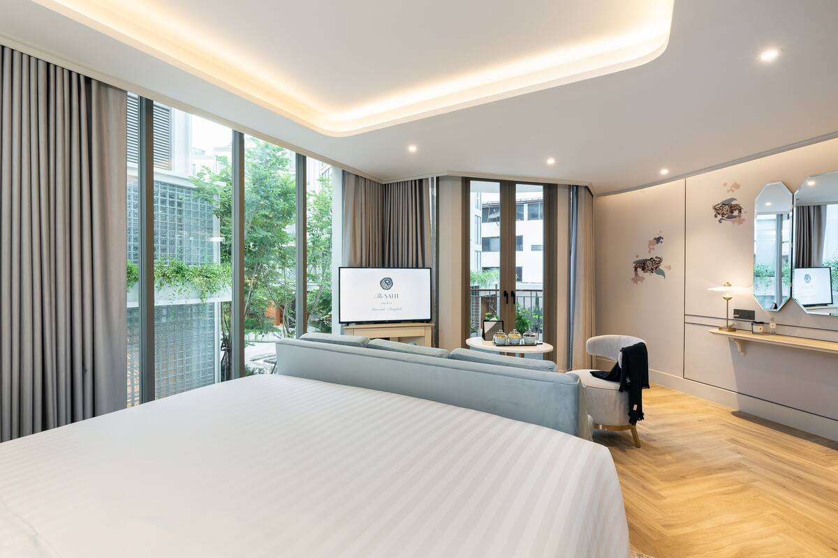Een moderne hotelkamer met een groot bed, een televisie, een zithoek en uitzicht op de stad.