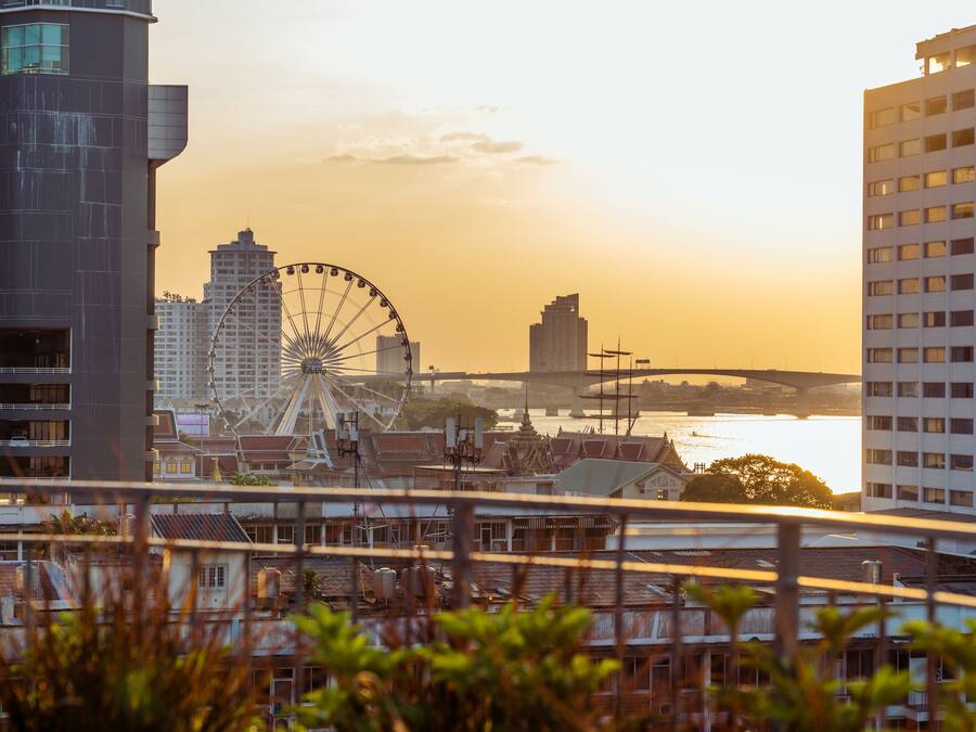 A cityscape with a Ferris wheel, modern buildings, and a river.