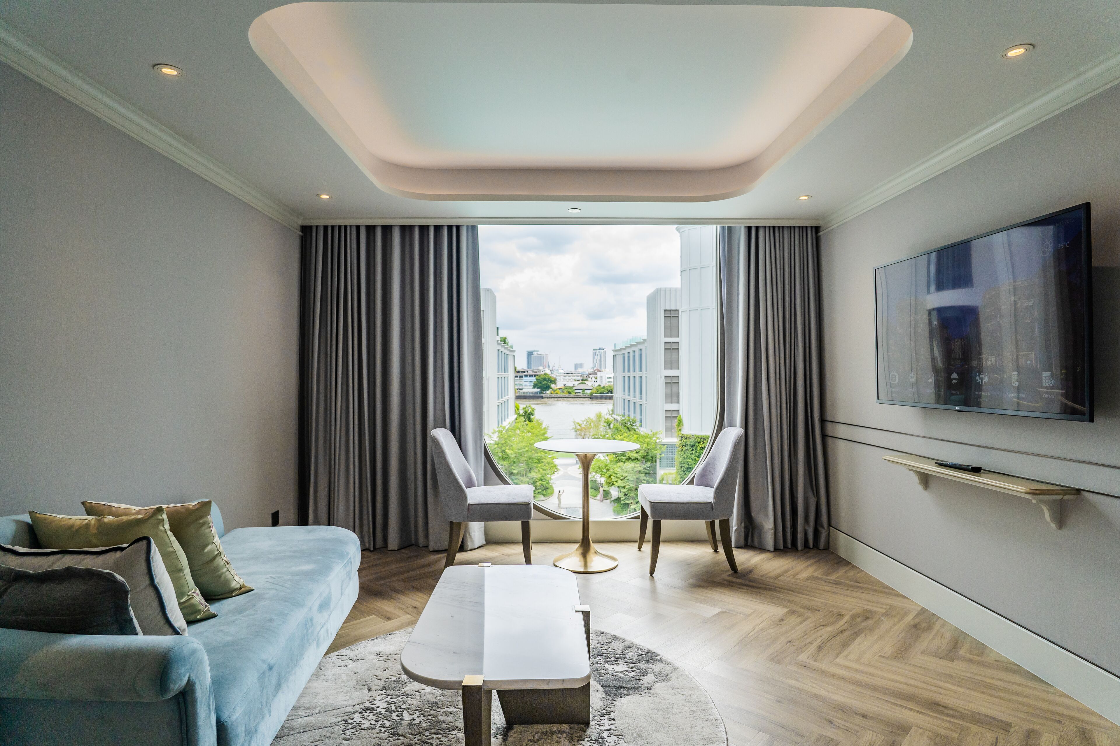 Una sala de estar moderna con un sofá, dos sillones, una mesa de centro y un televisor montado en la pared.