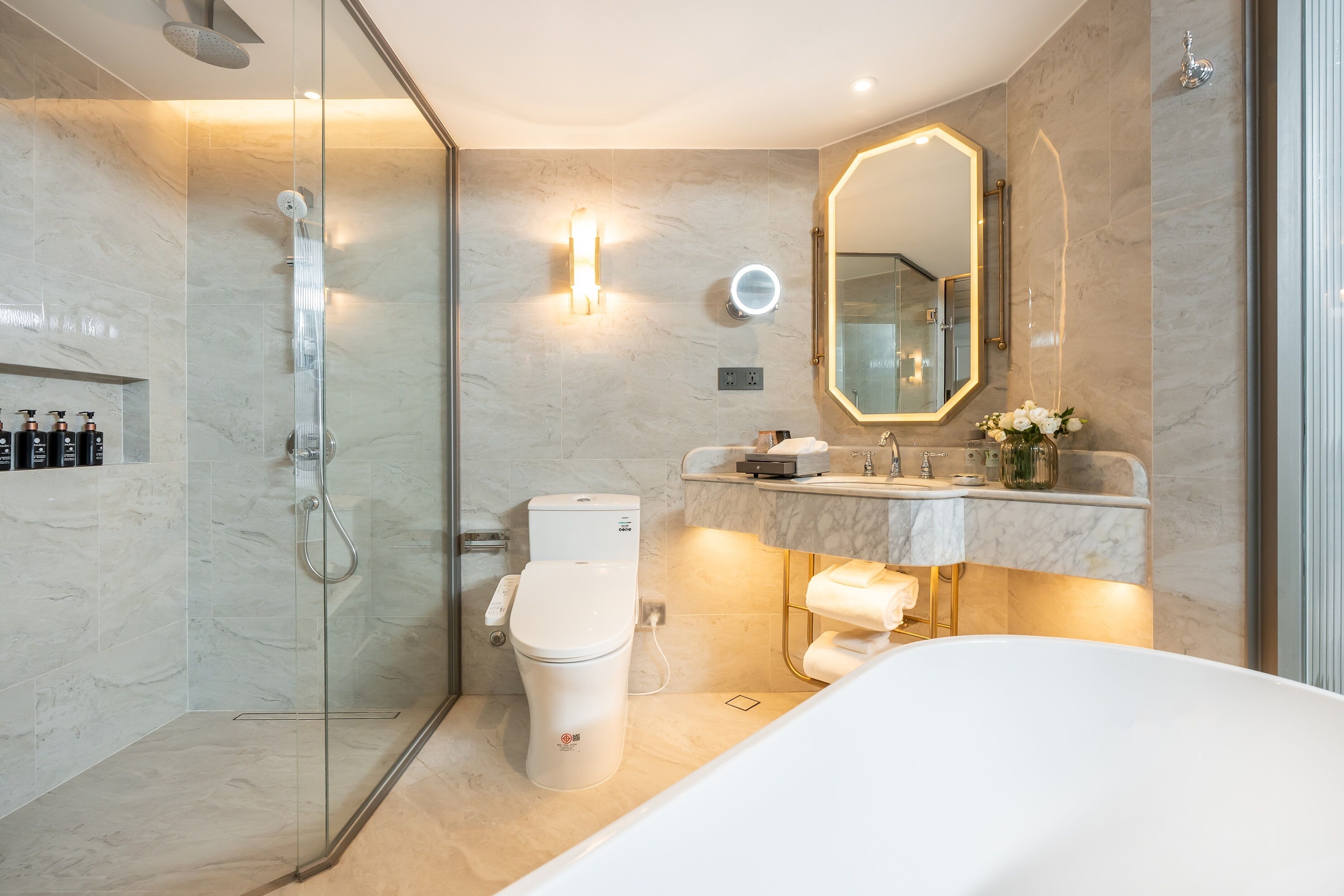 A modern bathroom with a glass-enclosed shower, a toilet, a sink with a mirror, and a bathtub.