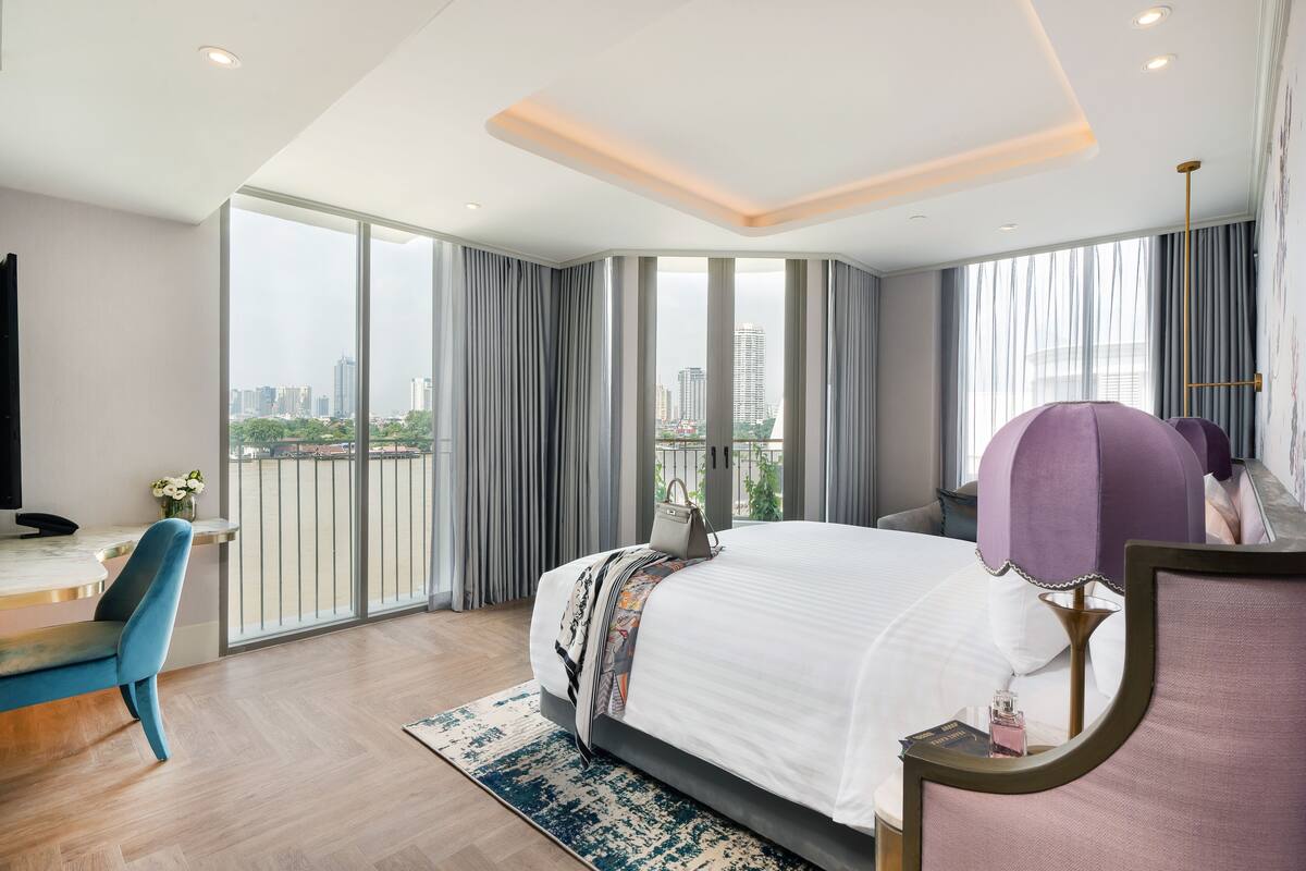 Een moderne hotelkamer met een groot bed, een bureau en uitzicht op de stad.