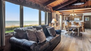 Un salon chaleureux avec un canapé en cuir, un coin repas avec des chaises en bois et une vue sur l ’océan.