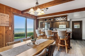 Un intérieur en bois avec une table à manger, des chaises et une vue sur l’océan.
