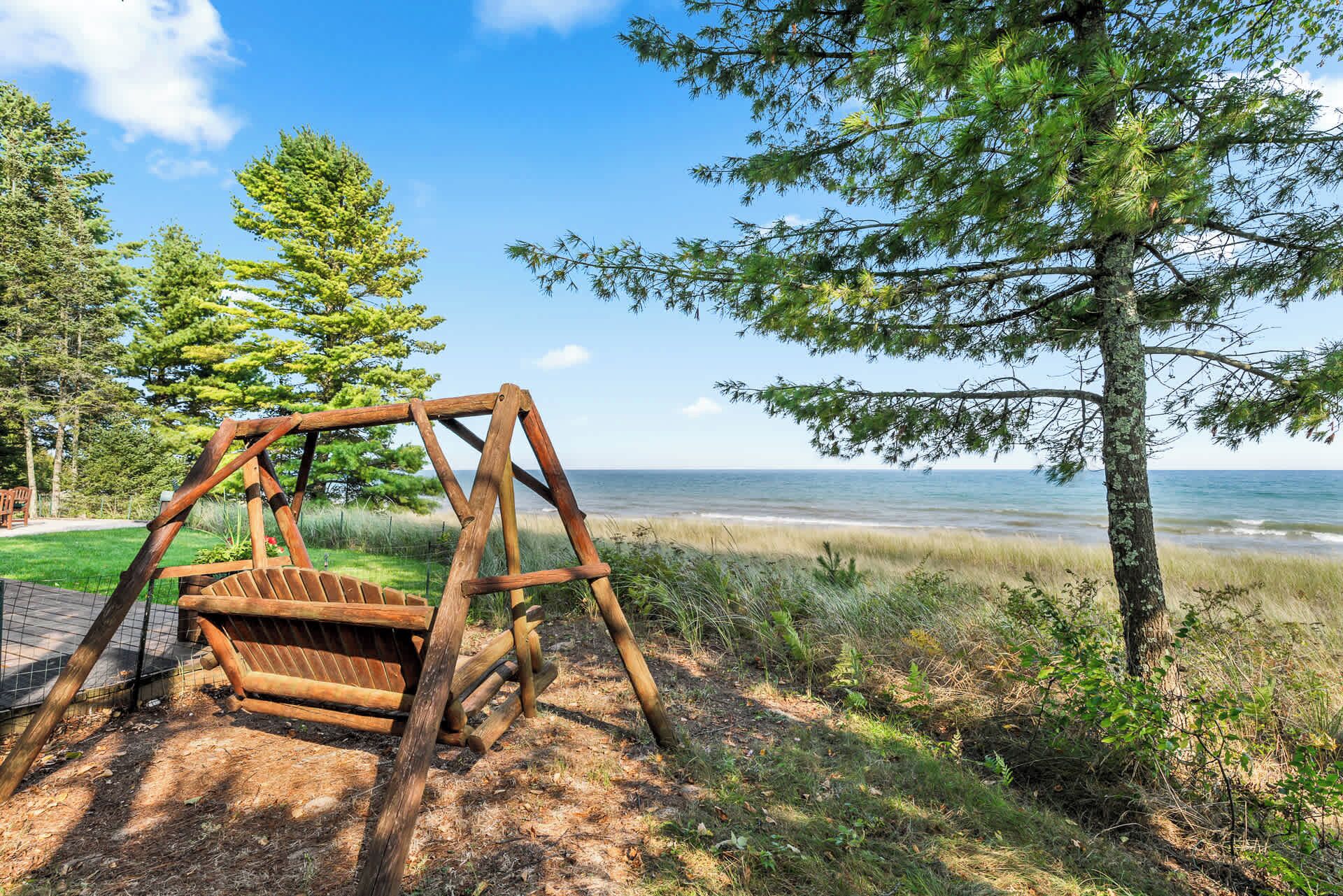 En gungställning i trä nära en strand med utsikt över havet.