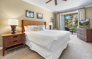 A hotel room with a large bed, two bedside tables, a desk with a chair, and a view of the outdoors.